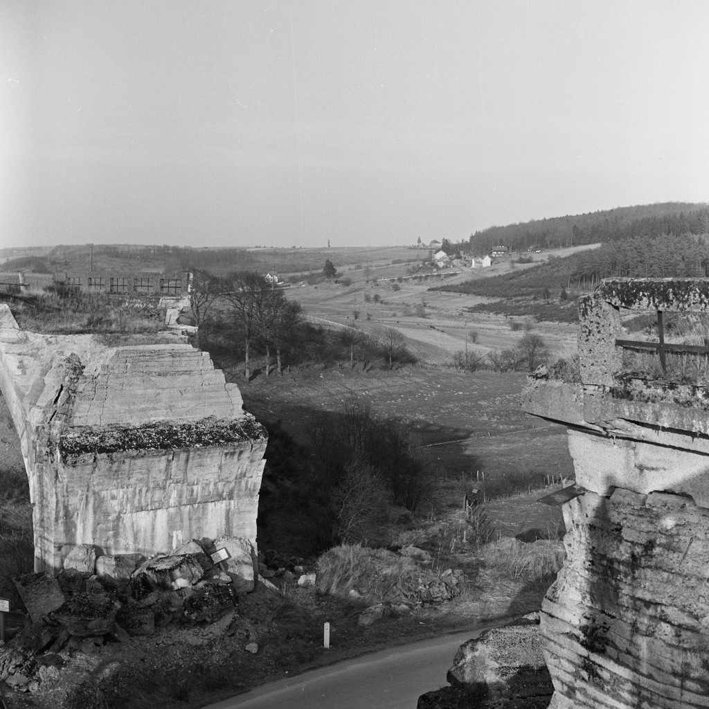 Un pont de la ligne de la Vennbahn détruit pendant la Seconde Guerre mondiale, près de Saint-Vith. Dans l‘après-guerre, les politiciens ont rechigné à payer les frais considérables nécessaires pour reconstruire tous les viaducs sur l‘ensemble de  la ligne de la Vennbahn. Pour cette raison, seulement quelques tronçons de la Vennbahn ont été exploités. En 1961, à partir de Luxembourg, les trains ne circulaient plus qu‘entre Wilwerdange et Burg-Reuland en Belgique. (Photo Paul Aschman 1961, © Photothèque Ville de Luxembourg)